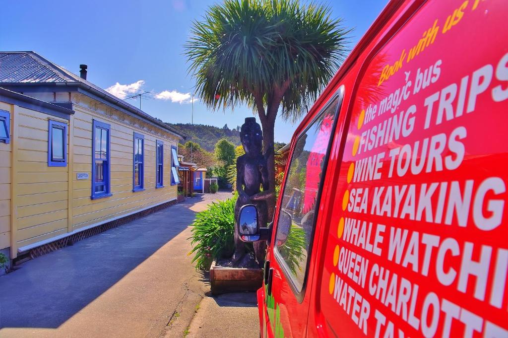 a red van parked next to a house with a palm tree at Sequoia Lodge Backpackers in Picton