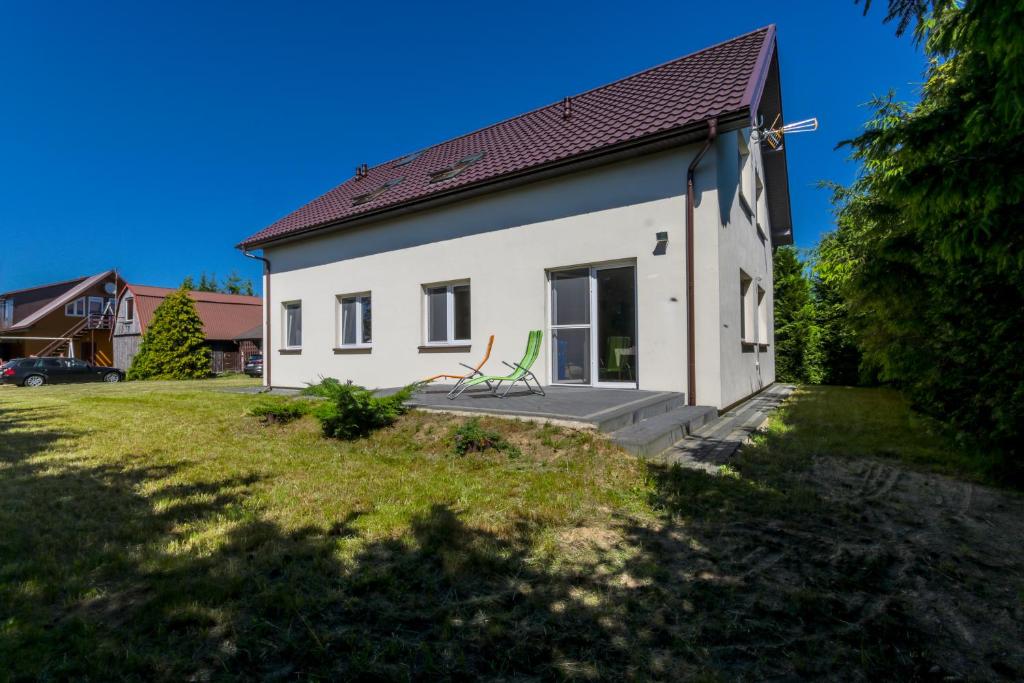 una casa blanca con una silla verde en un patio en Pokoje gościnne, nowy dom, cisza i spokój, Władysławowo en Władysławowo