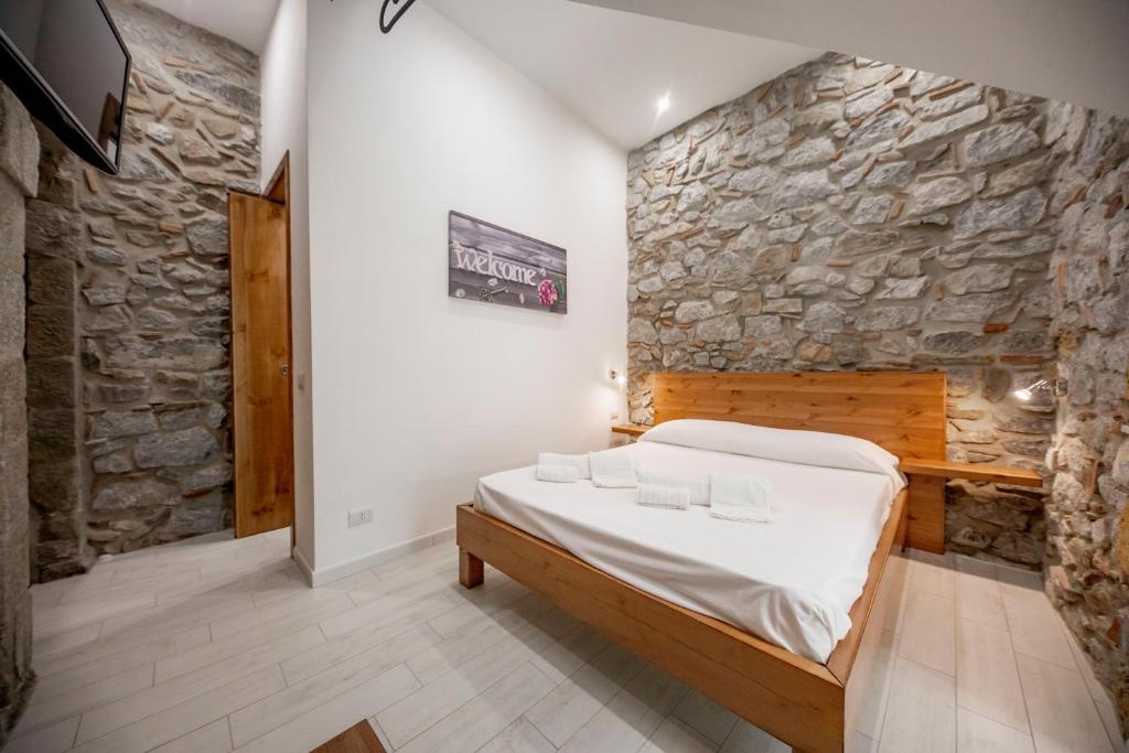 a bedroom with a bed and a stone wall at Hortensia House in Cefalù