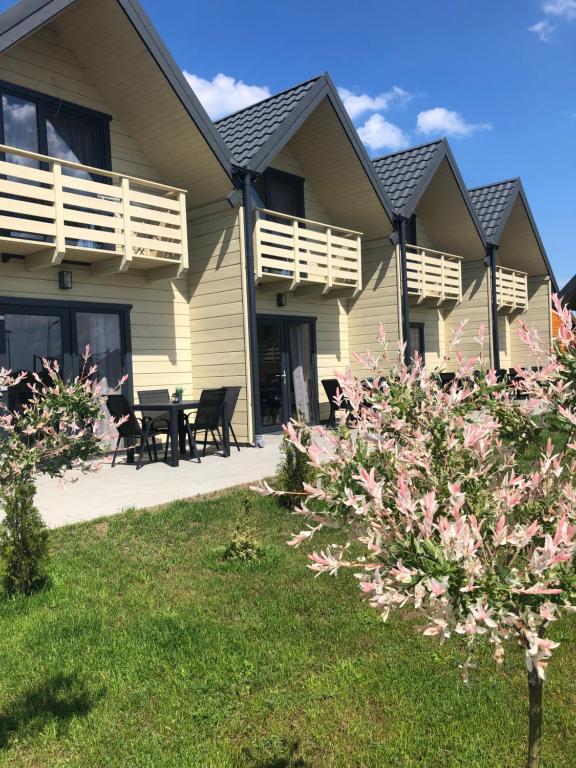 a house with a table and chairs in the yard at Domki Modrzewiowa 20 in Rewal