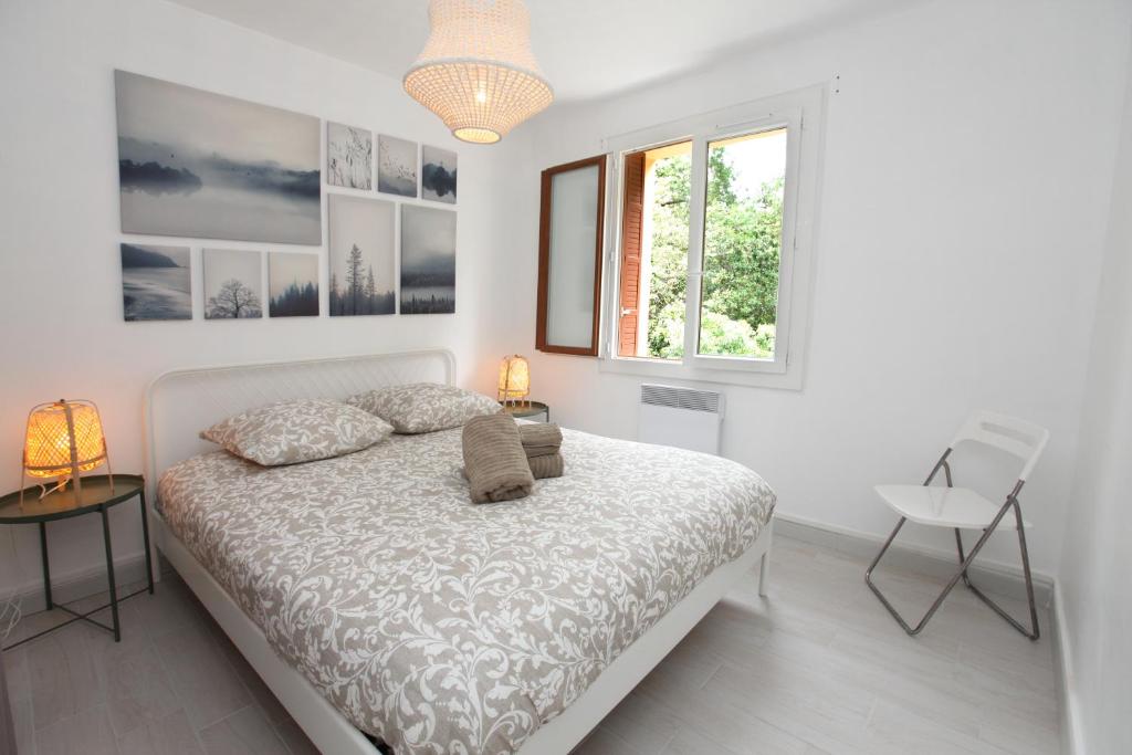 a white bedroom with a bed and a window at Résidence La Source in Toulon