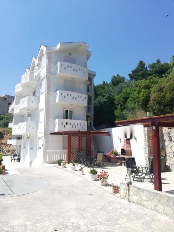 a large white building with chairs in front of it at Apartments Malou in Baška Voda