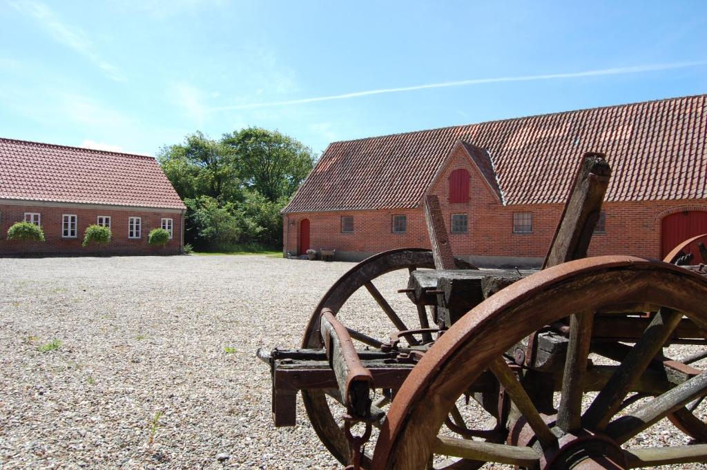 einem Holzwagen vor zwei roten Gebäuden in der Unterkunft Sdr. Grønkær Bed & Breakfast in Bækmarksbro