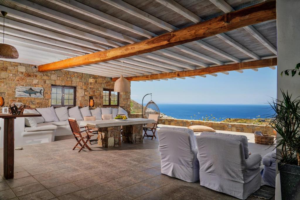 a patio with a table and chairs and the ocean at Elia Horizon Mykonos in Elia Beach