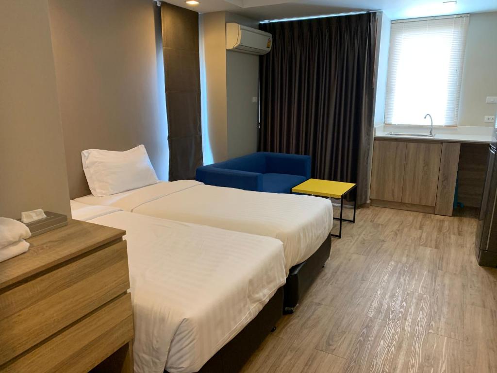 A twin room with two beds, a blue armchair and a kitchenette-style counter by the window.