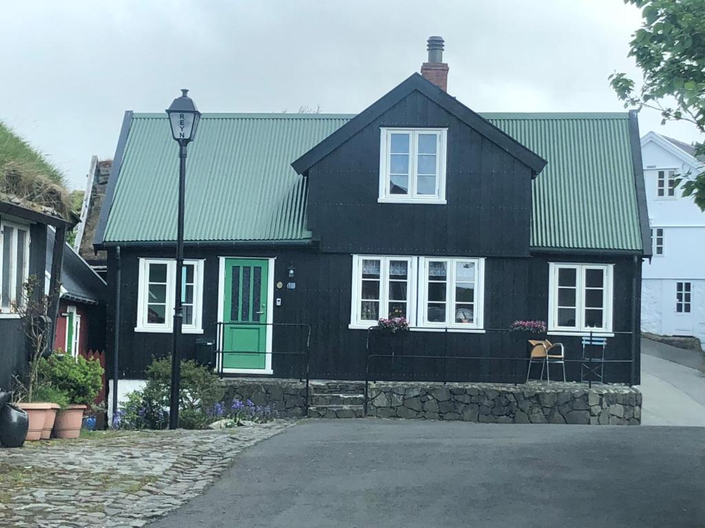 una casa negra con una puerta verde y una luz de la calle en A pearl in the center of the center of Thorhavn, en Tórshavn