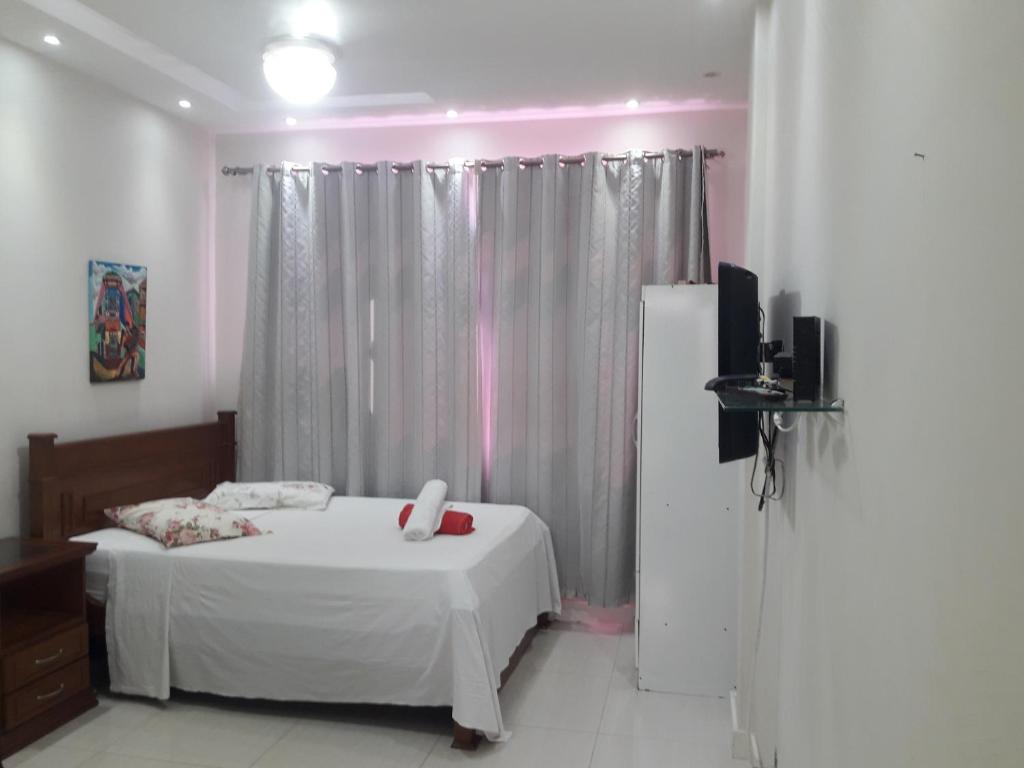 1 dormitorio con 1 cama blanca y TV en Studio Santa Clara, en Río de Janeiro