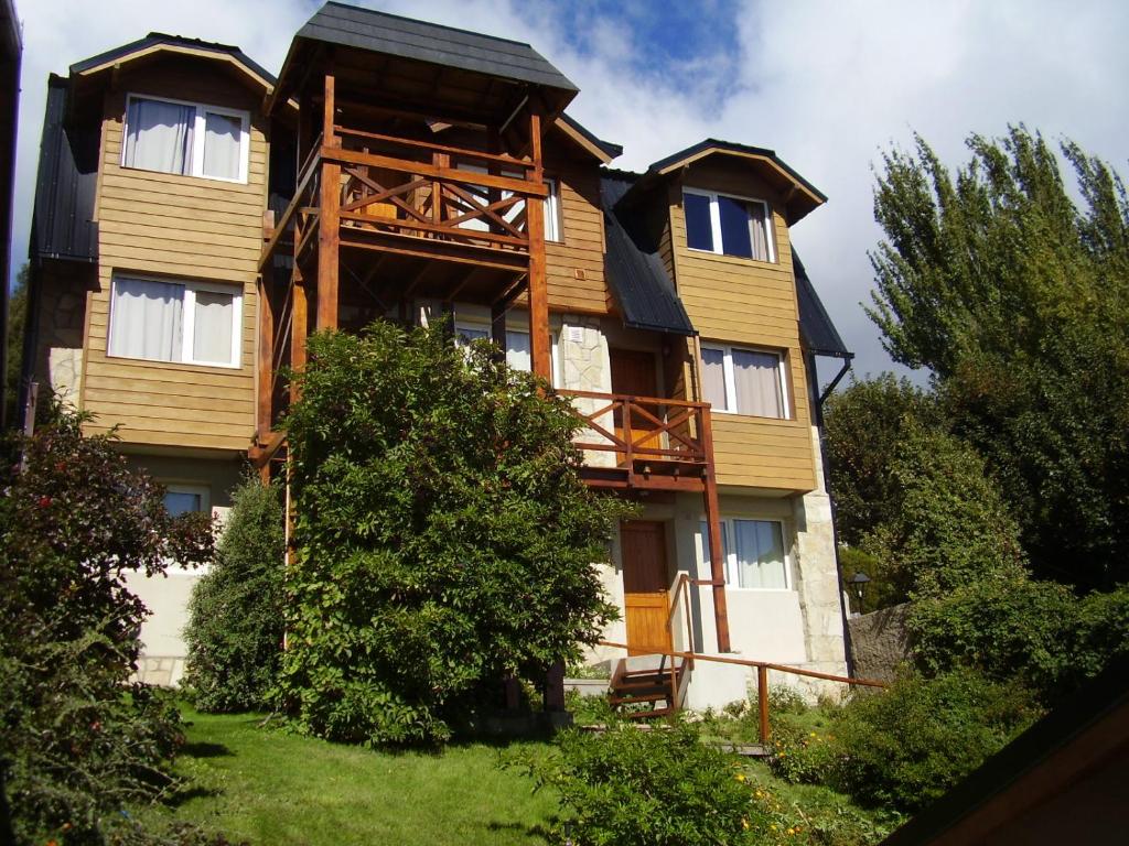 uma grande casa de madeira com árvores em frente em Departamentos Altos del Centro em San Carlos de Bariloche