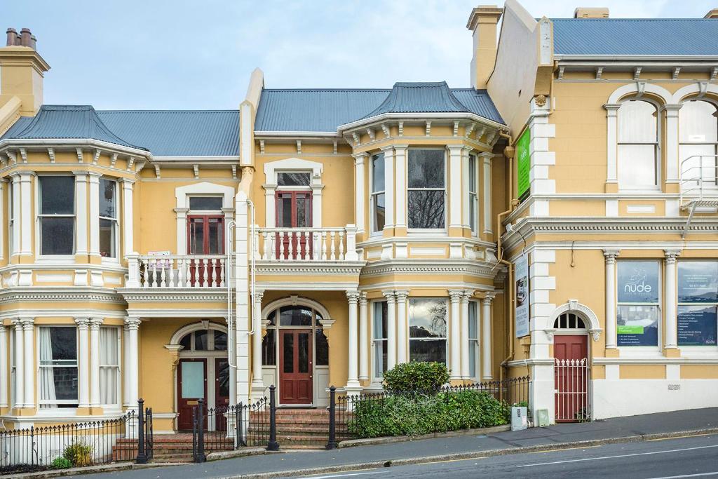a large yellow house on a city street at The Stuart Street Terraced House in Dunedin