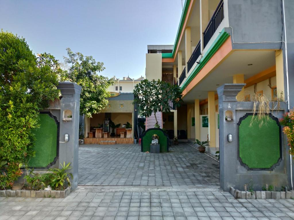 un patio de un edificio con puertas verdes y árboles en Beji Ayu Homestay, en Seminyak