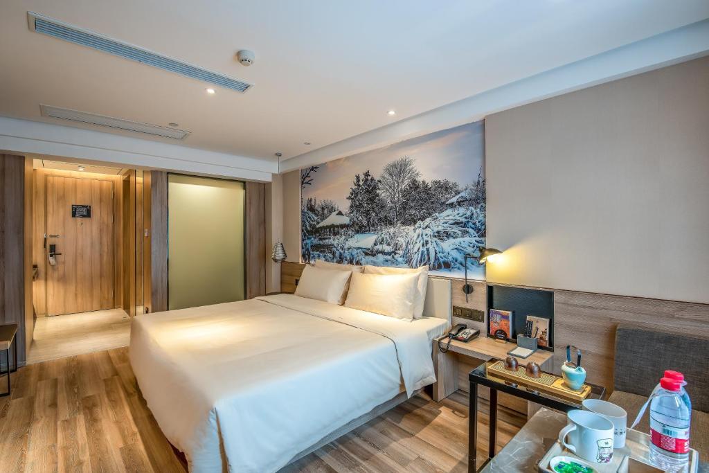 a bedroom with a white bed and a painting on the wall at Atour Hotel Hangzhou West Lake in Hangzhou