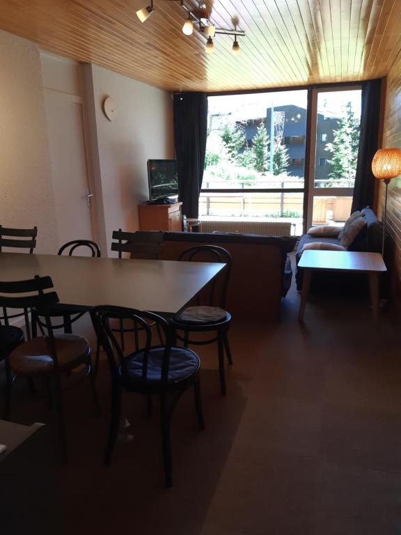 a dining room with tables and chairs and a window at Chamrousse 1750 - Le Taillefer - Appartement classé 3 étoiles in Chamrousse