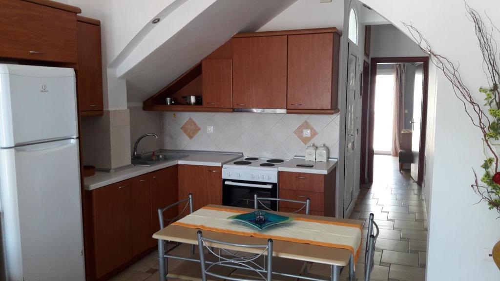 a kitchen with wooden cabinets and a table and a refrigerator at Apartment with Sea View... in Samos