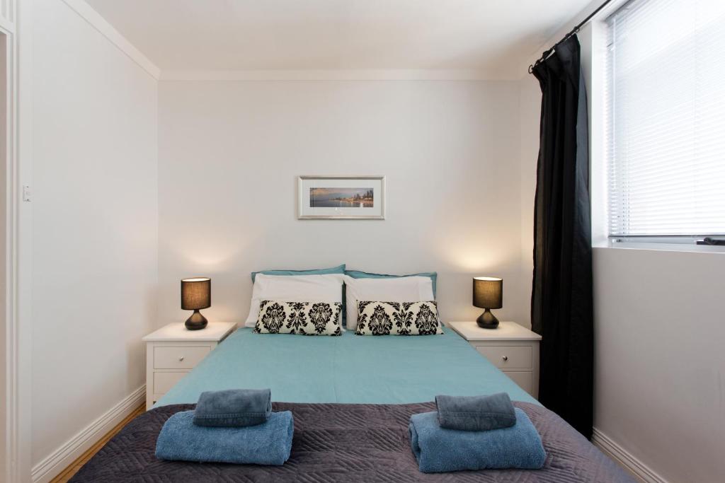 a bedroom with a blue bed with two pillows at Ocean Breeze Apartment in Fremantle