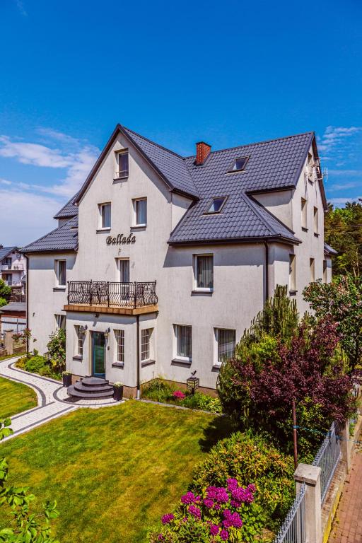 a large white house with a black roof at Willa Ballada in Kuźnica