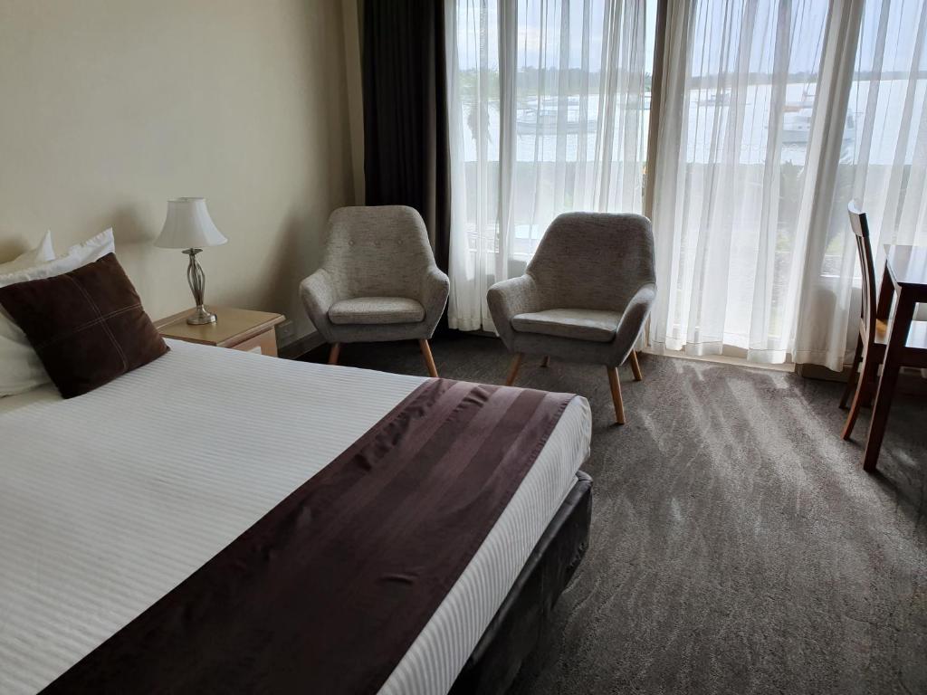 a hotel room with a bed and two chairs at Comfort Resort Waters Edge in Port Macquarie