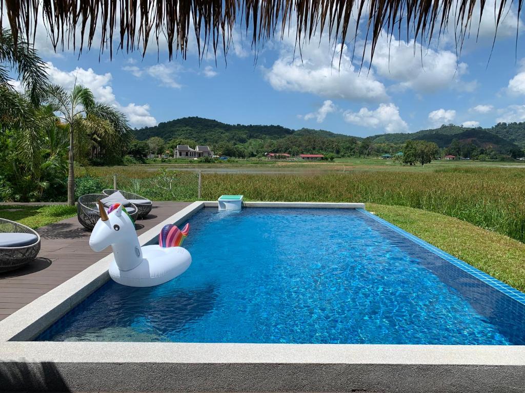 a swimming pool with a chair and a pool table at Cloud9 Holiday Cottages in Pantai Cenang