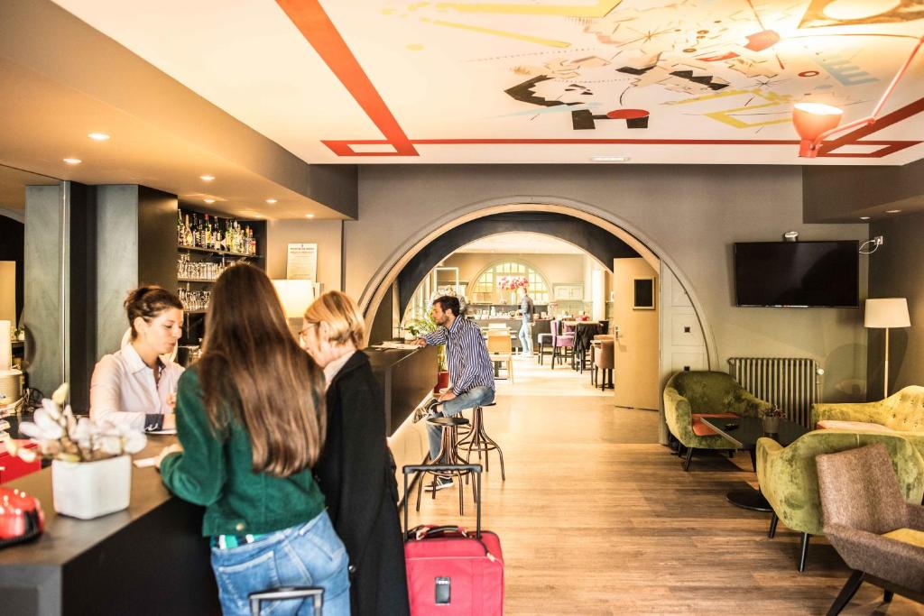 a group of people standing at a bar in a restaurant at Le Comte Rouge in Thonon-les-Bains