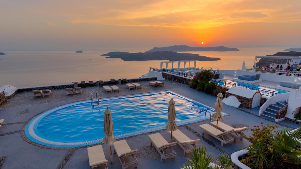 an image of a pool at a resort with the sunset at Caldera Butterfly Villas in Fira