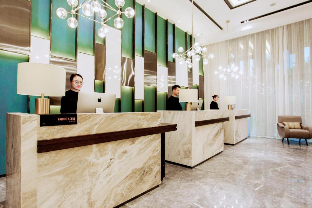 a lobby with three people sitting at a desk with laptops at Atour Hotel Xi'an Gaoxin Jinye Road Branch in Xi'an