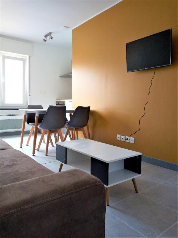 un salon avec une table et une télévision au mur dans l'établissement Merlimont Plage - Paola, à Merlimont