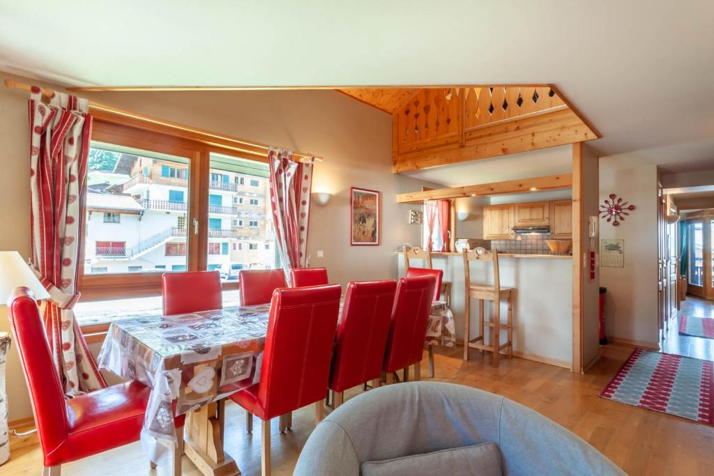 uma sala de jantar com uma mesa e cadeiras vermelhas em LA PLOCHE 6 em Morzine