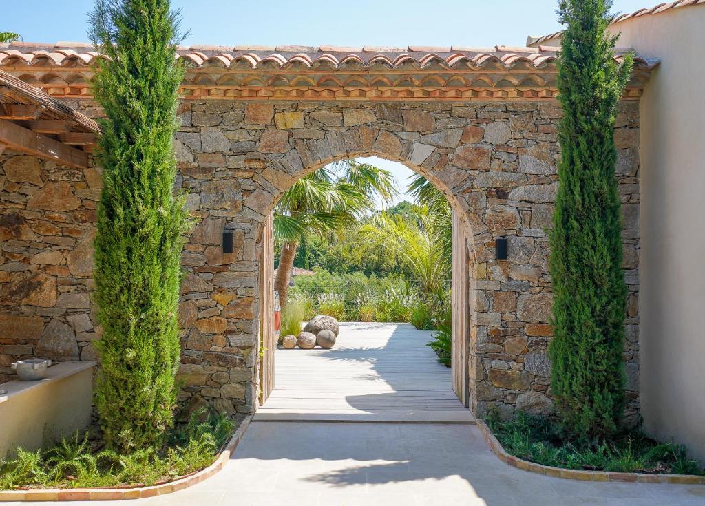 an archway in a stone wall with trees at villa Sant-Anna in Saint-Tropez