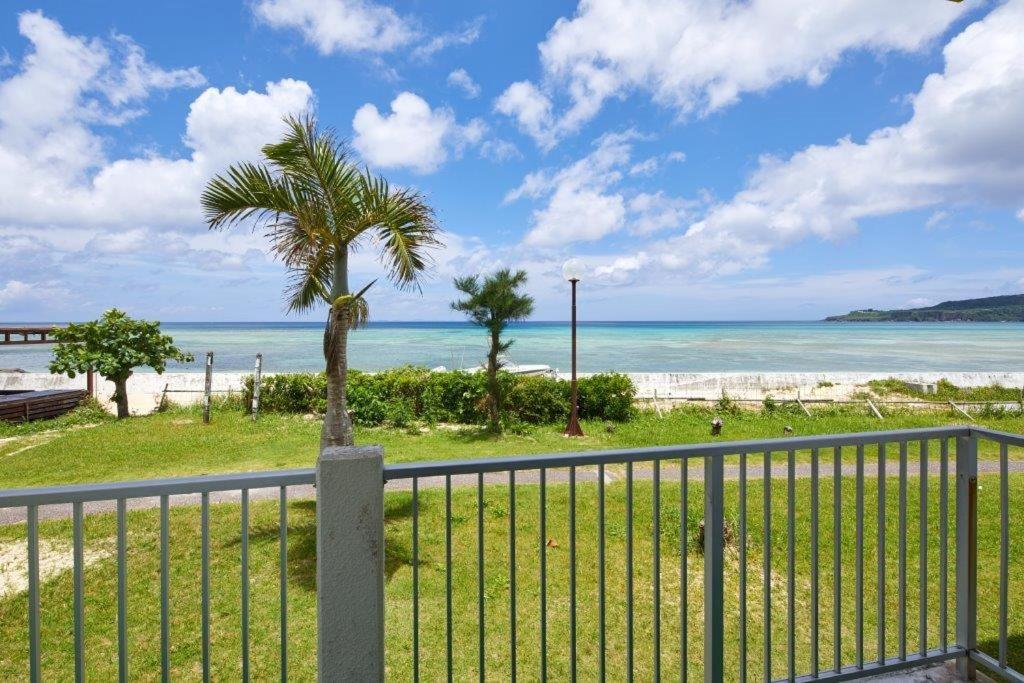 una palmera en una valla cerca de la playa en Resort Hotel Bel Paraiso, en Nakijin