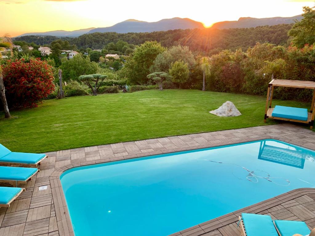 einen Pool in einem Garten mit Stühlen und Sonnenuntergang in der Unterkunft Villa Angel in La Gaude