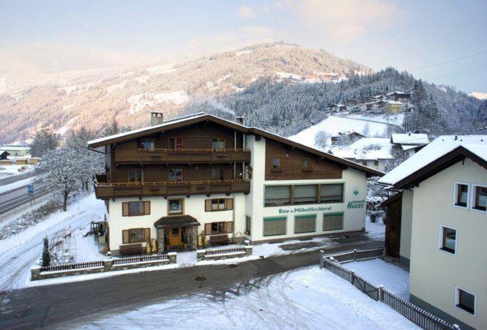 a building in the snow in front of a mountain at Appartement Andrea Hauser - Riedltischler in Zell am Ziller