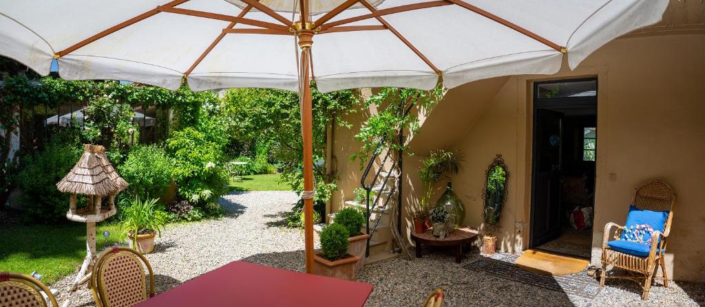 a patio with an umbrella and a table and chairs at Côté Jardin, Chambres d’hôtes B&B in Le Pont-de-Beauvoisin