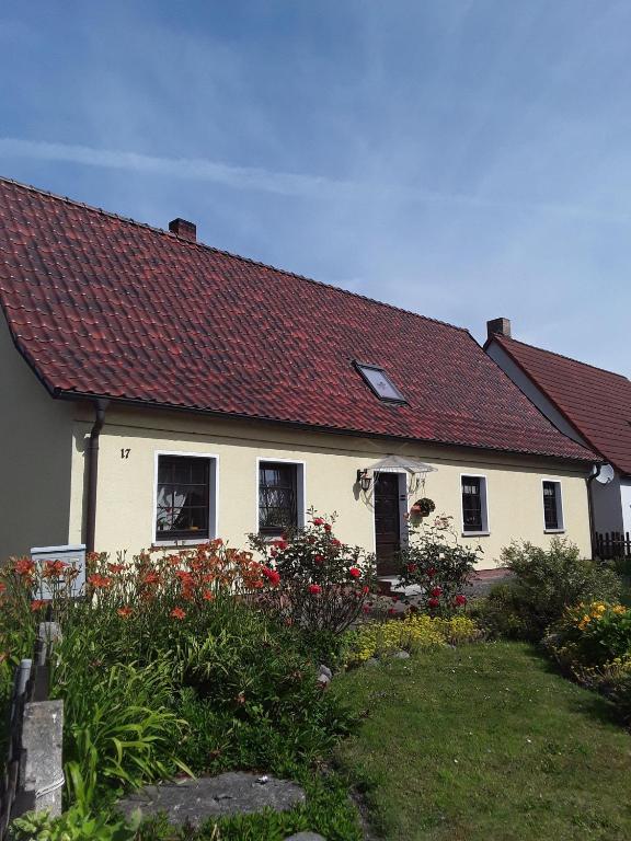 a white house with a red roof and some flowers at Ferienwohnung-Lalka in Altenkirchen