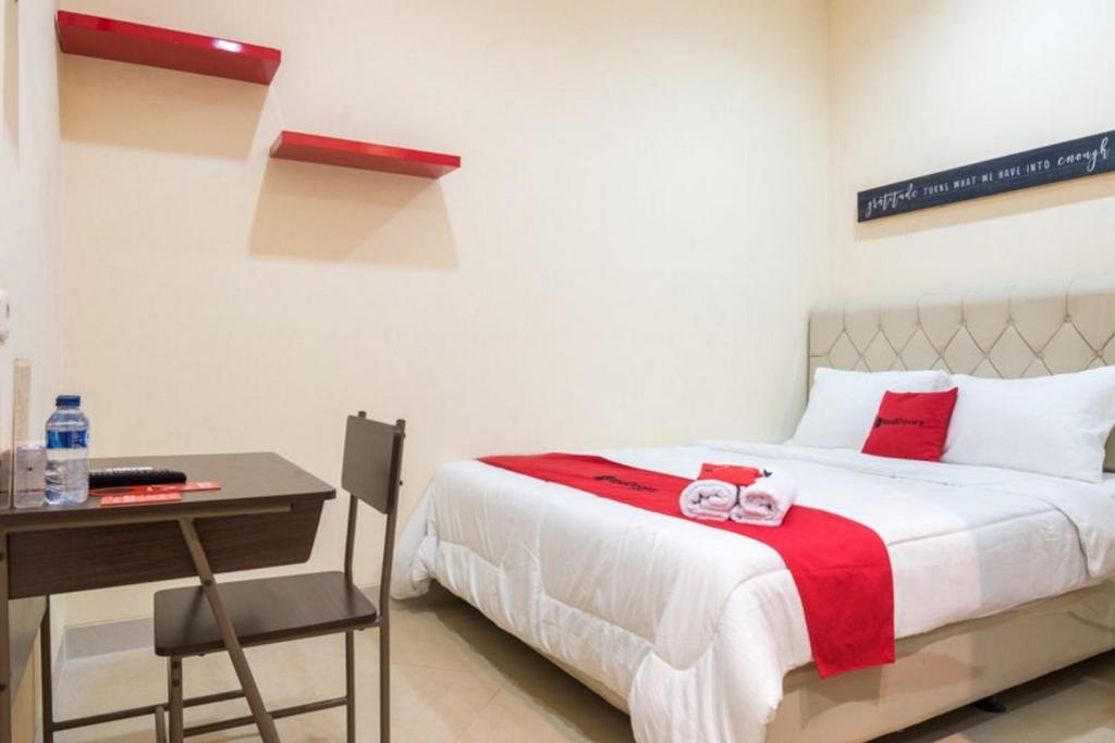a bedroom with a bed and a desk with two stuffed animals on it at RedDoorz At Tebet Barat 2 in Jakarta