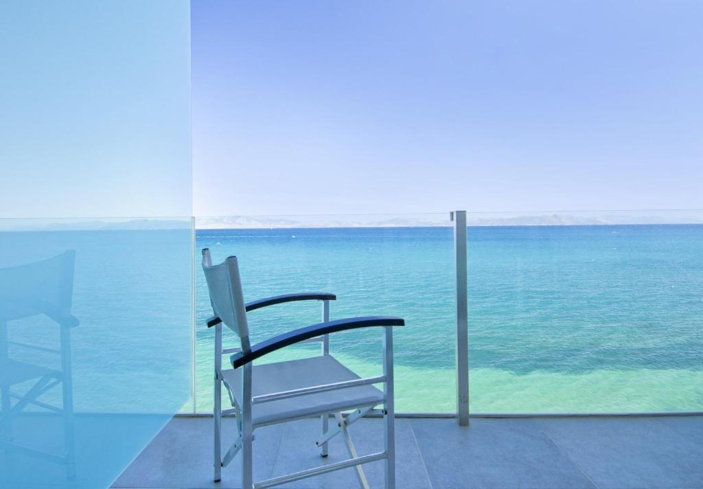 two chairs sitting on a balcony looking out at the ocean at Kos Aktis Art Hotel in Kos