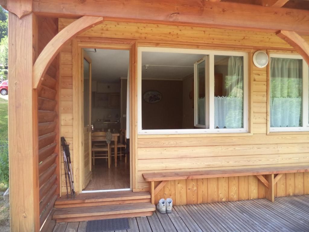 a front porch of a wooden cabin with a large window at Studio Lou Kiwi - Résidence Bec de l Aigle in Le Lioran