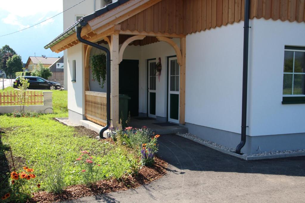 a white house with a porch with a wooden roof at Ferienwohnung Lisa in Bad Mitterndorf