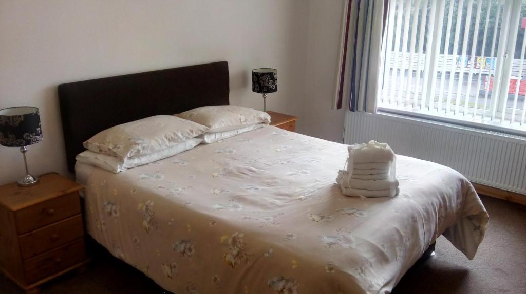 a bedroom with a bed with white sheets and a window at Dawlish Holiday Apartment in Dawlish