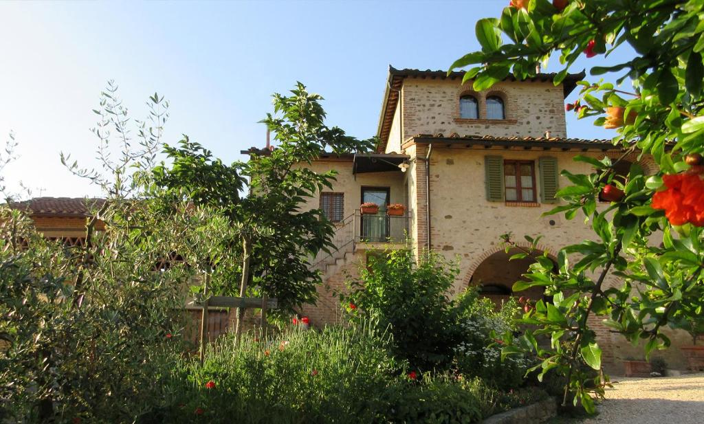 un ancien bâtiment avec un jardin en face de celui-ci dans l'établissement Podere Chiocciola, à Poggibonsi