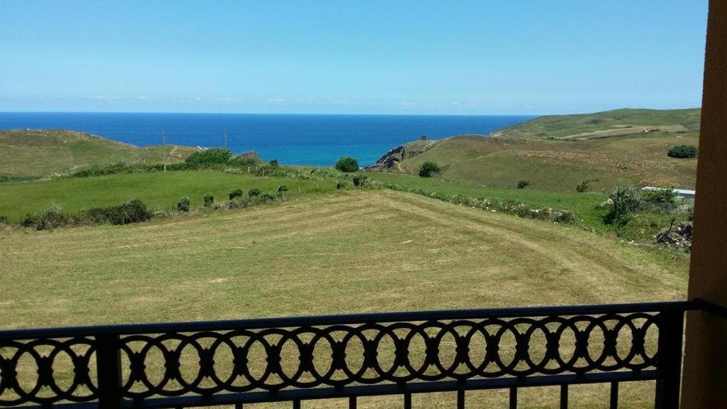 uma varanda com vista para um campo e para o oceano em APARTAMENTOS EL SOLO em Santillana del Mar