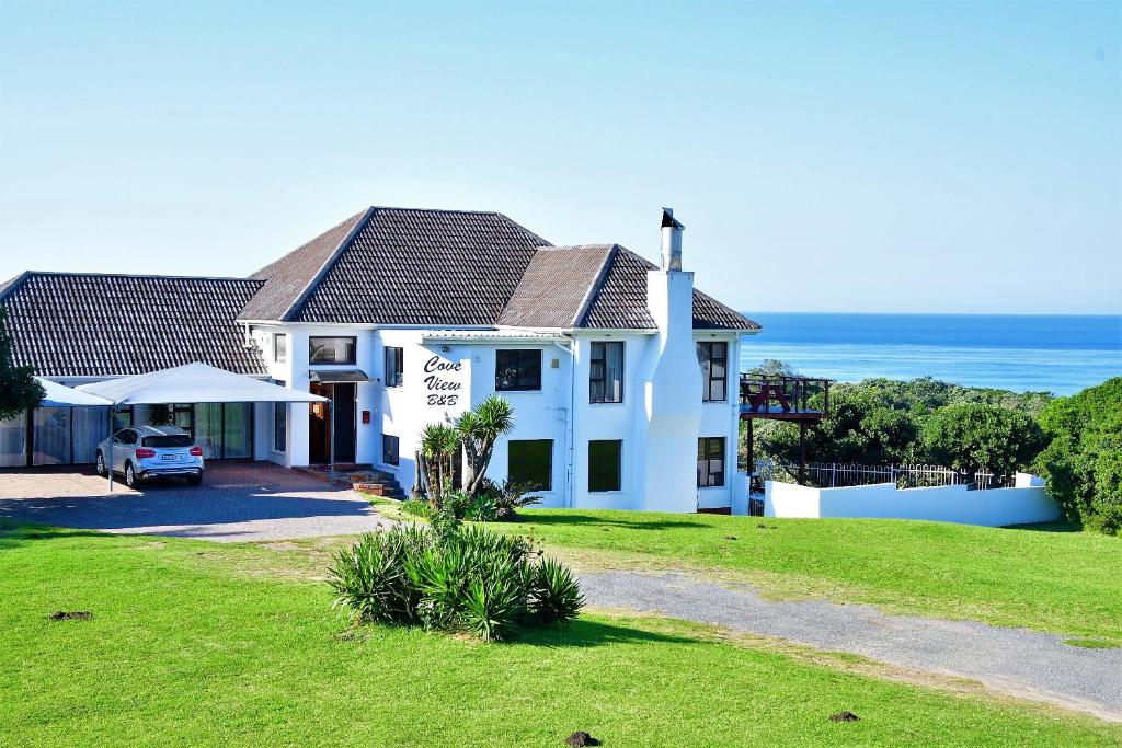 a white house with the ocean in the background at Cove View B&B in East London