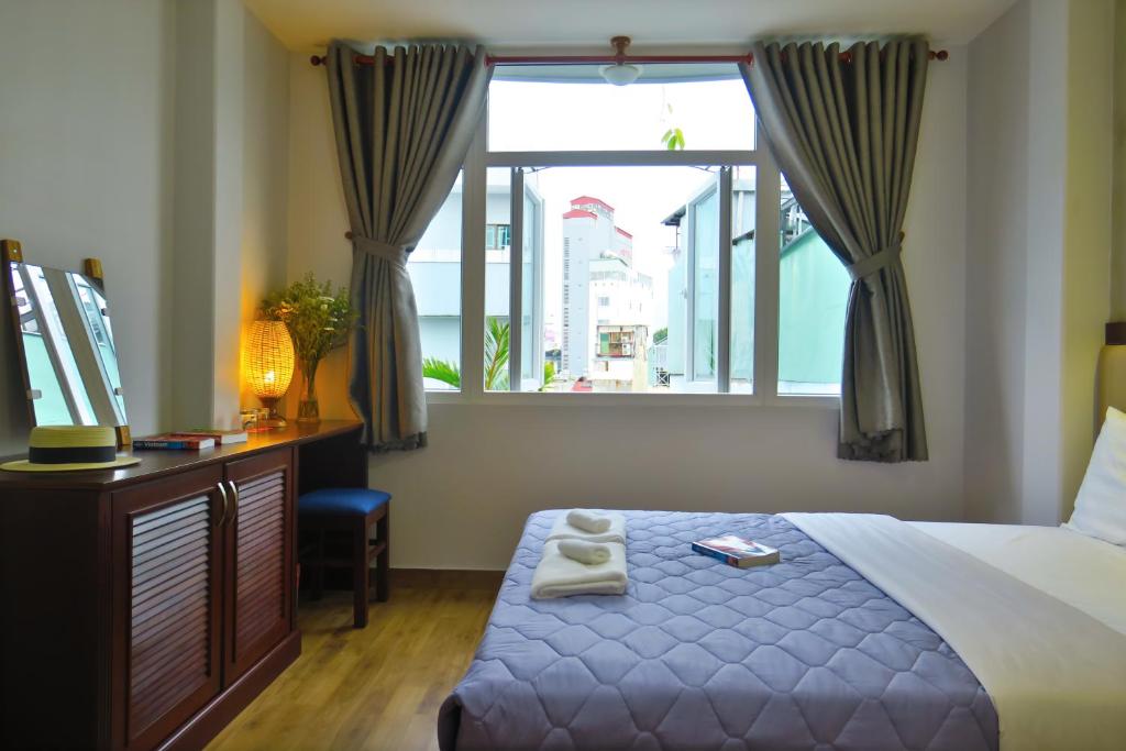 een slaapkamer met een bed, een raam en een bureau bij Giang Son Hotel 江山民宿胡志明市 in Ho Chi Minh-stad