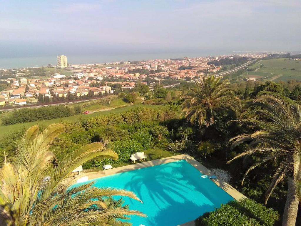 een blauw zwembad met palmbomen en een stad bij Villa Capodarco B&B in Porto San Giorgio