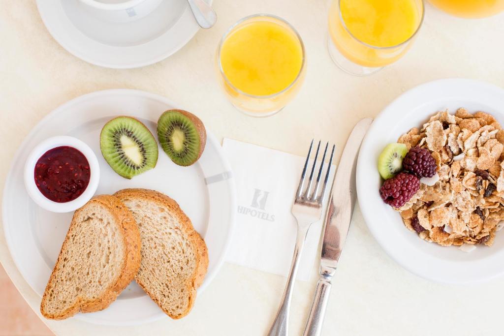 a table with two plates of food with toast and fruit at Hipotels Barrosa Park in Chiclana de la Frontera