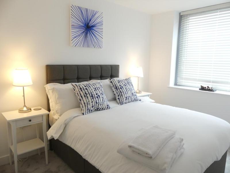 a bedroom with a large white bed with a window at Churchill Place - Downtown Luxury Apartments in Basingstoke