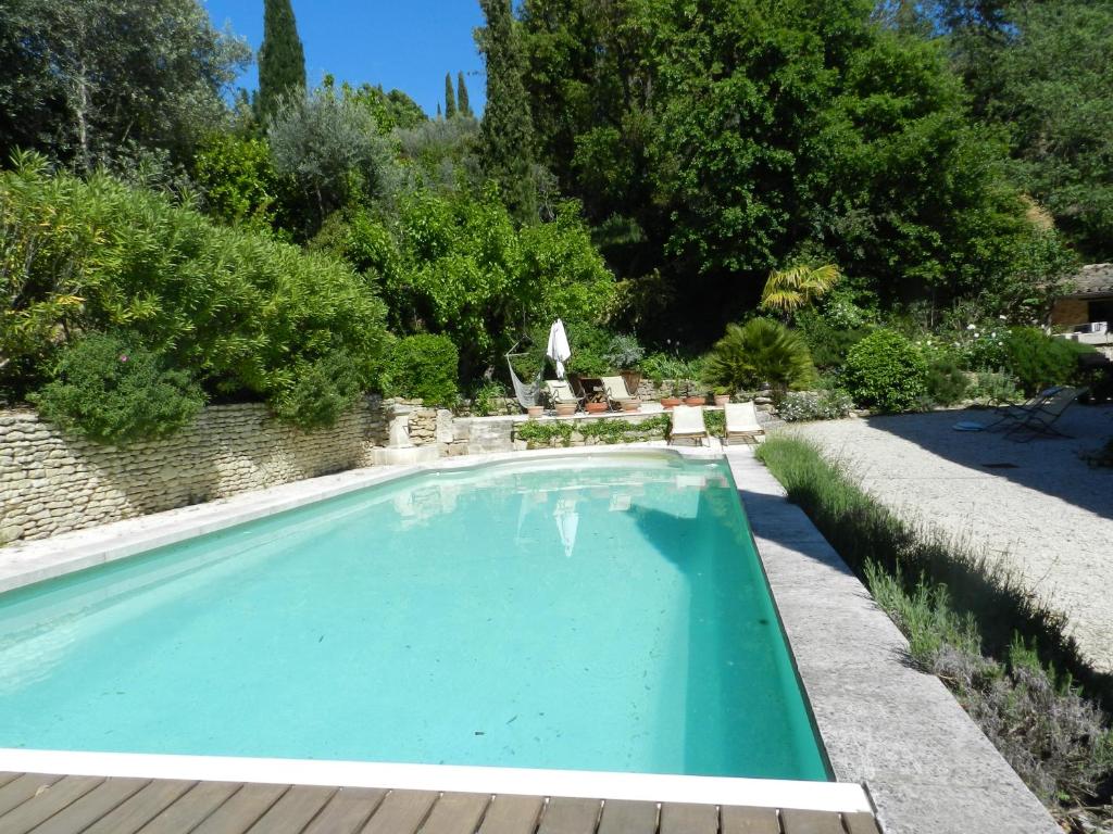 una piscina en un jardín con árboles y arbustos en Les Acanthes en Lauris