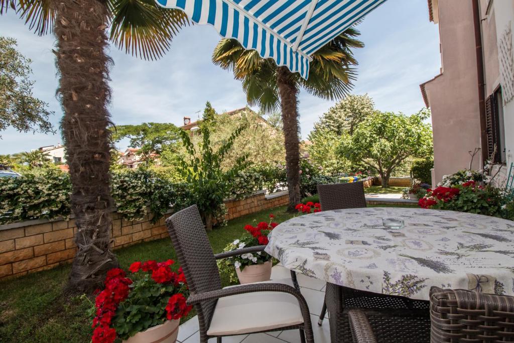 un patio con mesa, sillas y palmeras en Apartments Mila en Rovinj