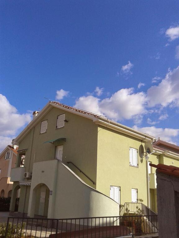 a yellow house with a fence in front of it at Apartman Igor in Čižići