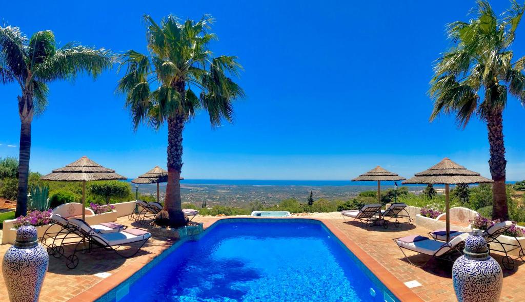 a swimming pool with palm trees and chairs at Monte Borboleta in Faro