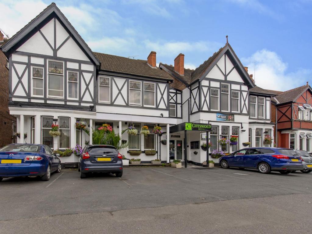 un gran edificio blanco y negro con coches aparcados en un aparcamiento en The Cotswold en Nottingham