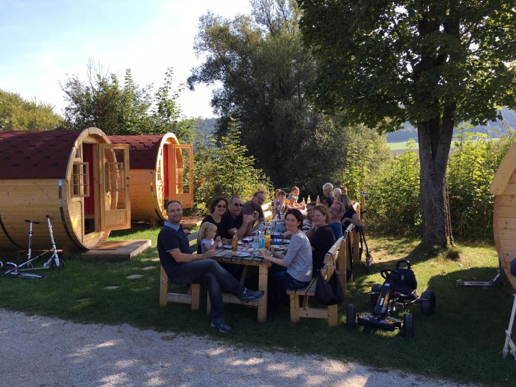 un grupo de personas sentadas en una mesa en el césped en NATURAMA BEILNGRIES - Naturparkcamping und Fasshotel, en Beilngries
